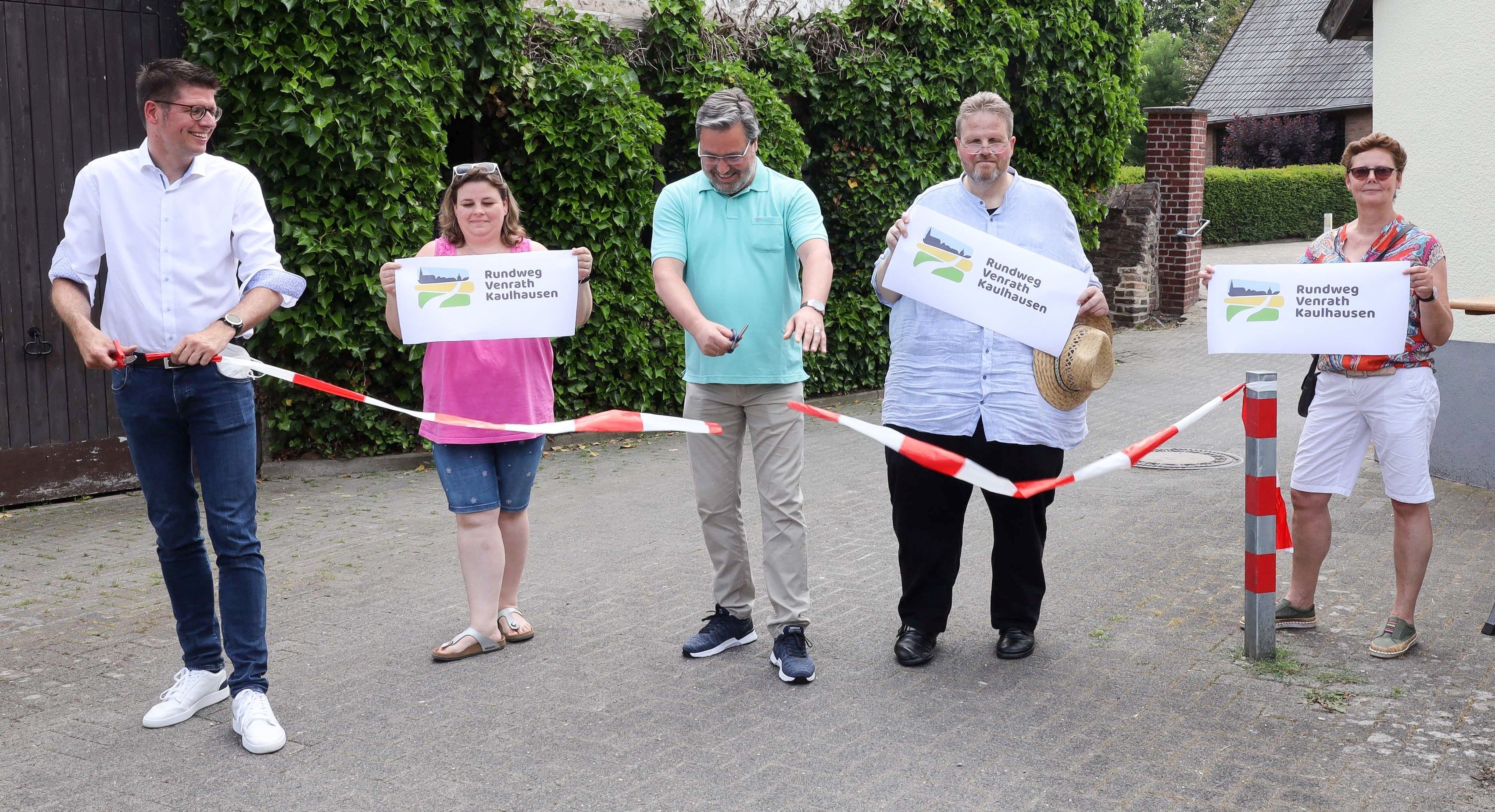 Rundweg Venrath-Kaulhausen offiziell eröffnet Bürgermeister Stephan Muckel (links) und Dorfforums-Sprecher Peter-Josef Gormanns (Mitte) durchschneiden das Flatterband und geben so symbolisch den Weg frei. Mit dabei Pia Wirtz-Schopiak, Vorstand Dorfforum (2. v. links), Ratsherr Rainer Merkens (4. v. links), Projektteamleiterin Friederike Grates.