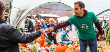 Stand mit Kürbissen auf dem Bauernmarkt auf Hohenbusch - eine Kundin nimmt Wechselgeld entgegen