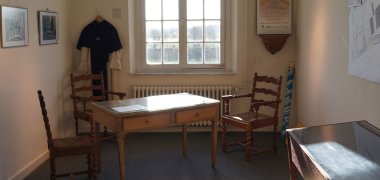 Blick in eine museale Zelle in Haus Hohenbusch, zusehen sind u.a. ein Schreibtisch mit 3 Stühlen