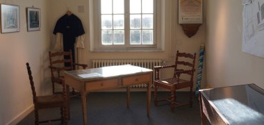 Dauerausstellung Blick in eine museale Zelle in Haus Hohenbusch, zusehen sind u.a. ein Schreibtisch mit 3 Stühlen