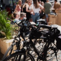 Im Vordergrund stehen Fahrräder, im Hintergrund Besucherinnen und Besucher