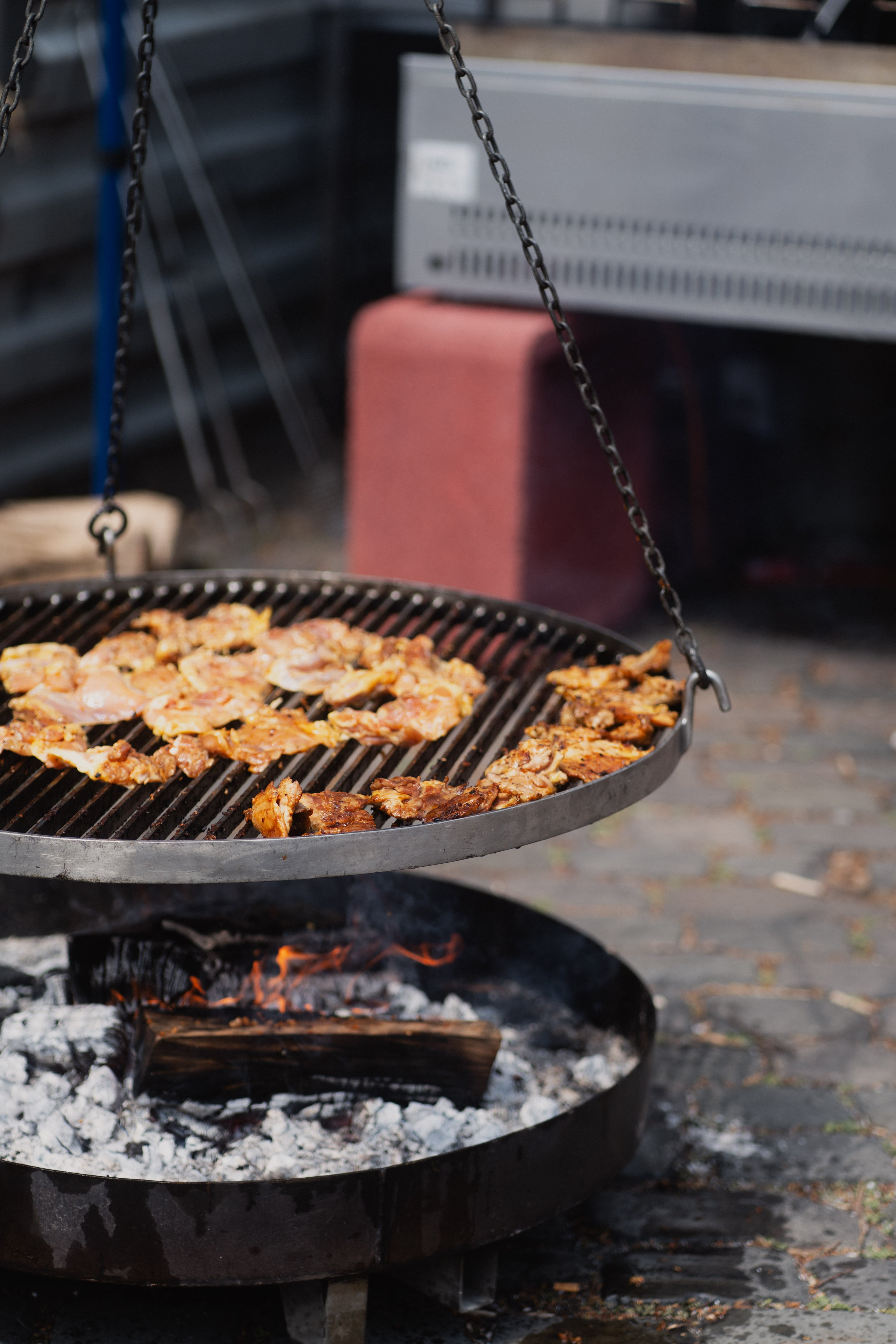 Auf einem Schwenkgrill wird Fleisch gegrillt.