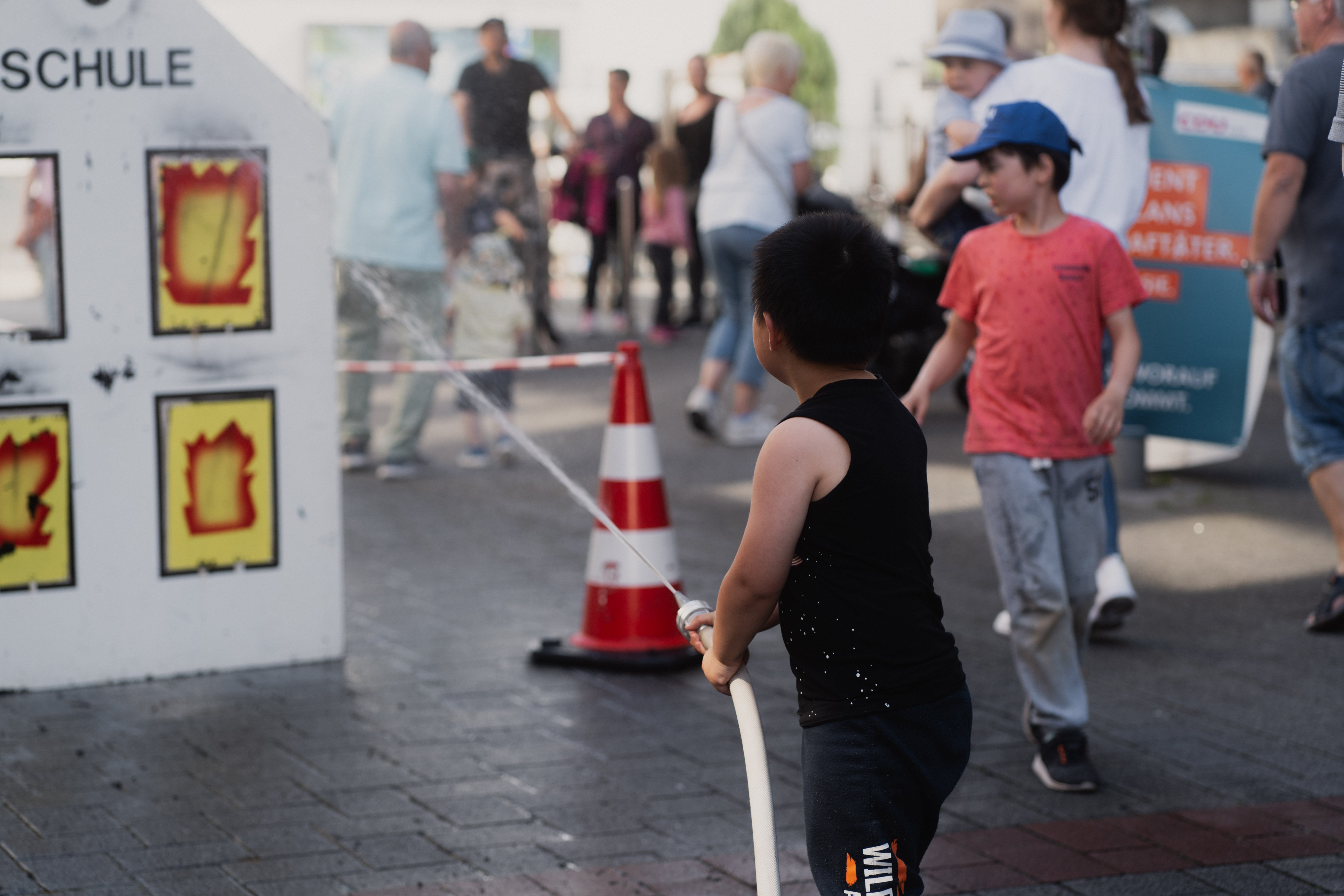 Kinder halten einen Feuerwehrschlauch