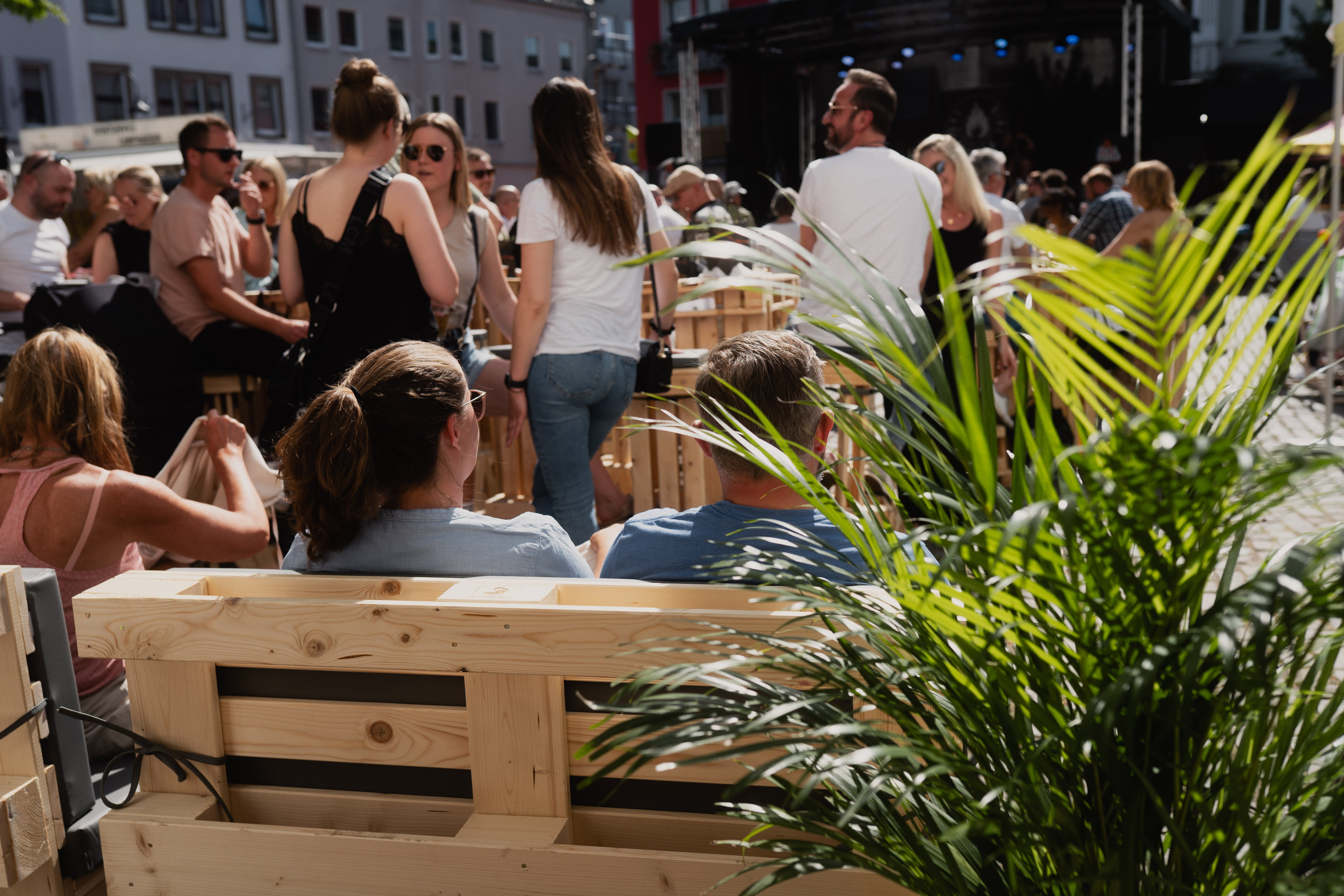 Viele Gäste beim Bike'n'BBQ, im Vordergrund steht eine Pflanze