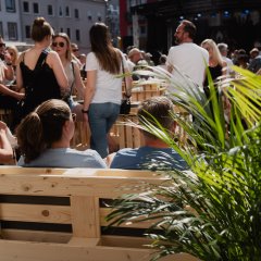 Viele Gäste beim Bike'n'BBQ, im Vordergrund steht eine Pflanze