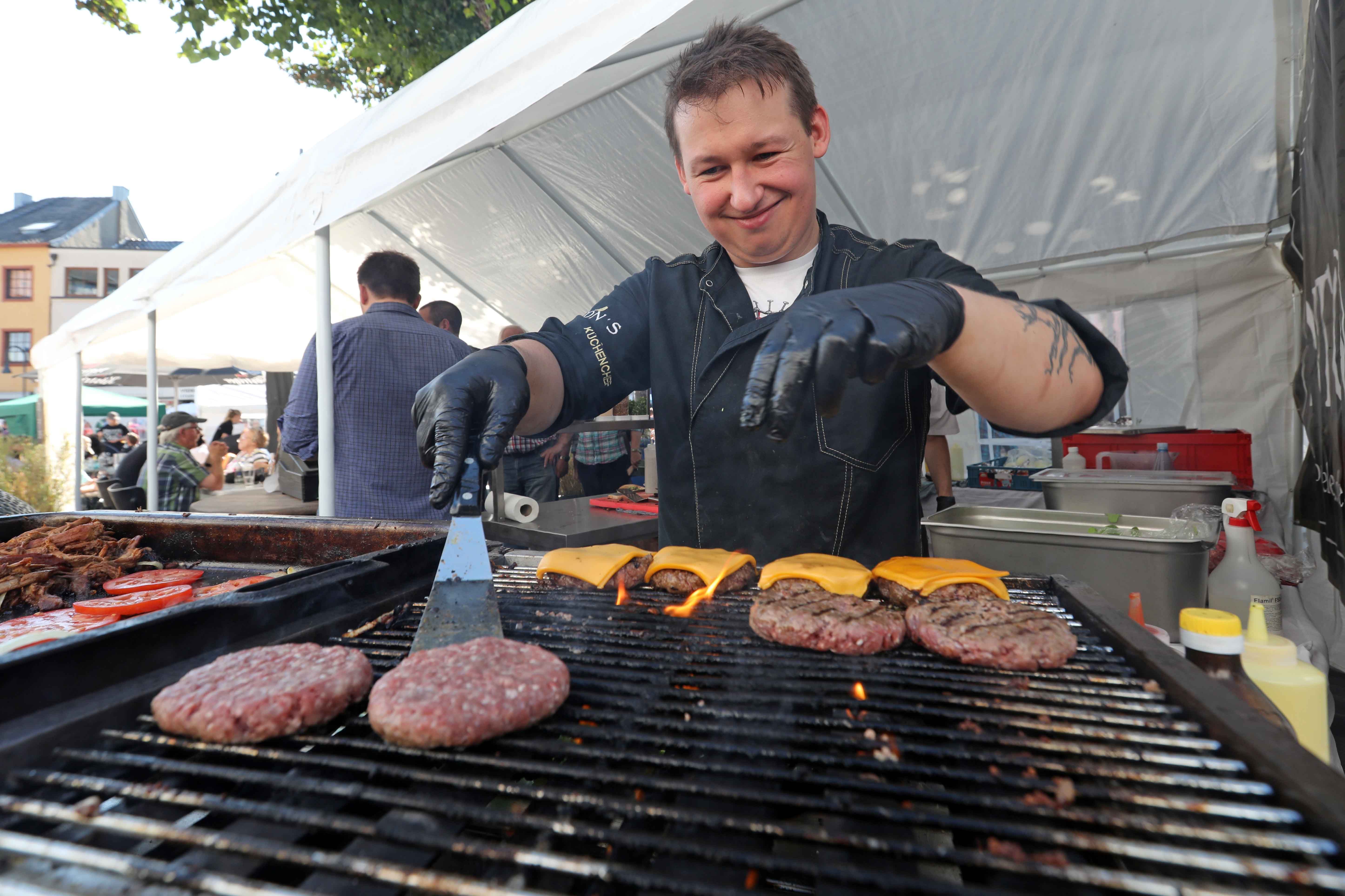 Auf einem Grill werden Burger gegrillt