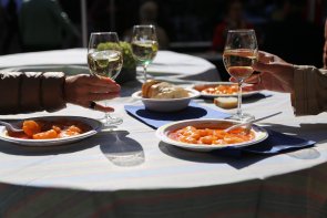 Wein und Speisen Auf einem Tisch stehen drei Teller mit Speisen und drei Gläser mit Wein. In der Mitte eine Schale mit Baguette.