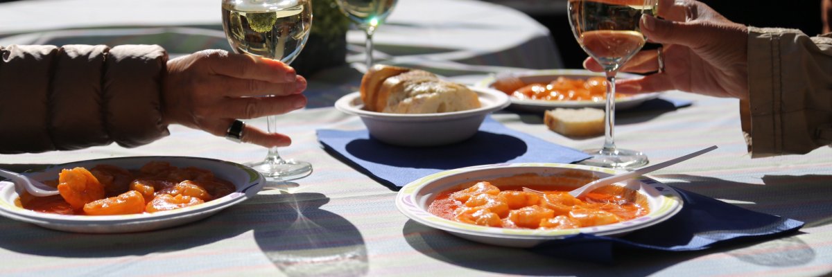 Wein und Speisen Auf einem Tisch stehen drei Teller mit Speisen und drei Gläser mit Wein. In der Mitte eine Schale mit Baguette.