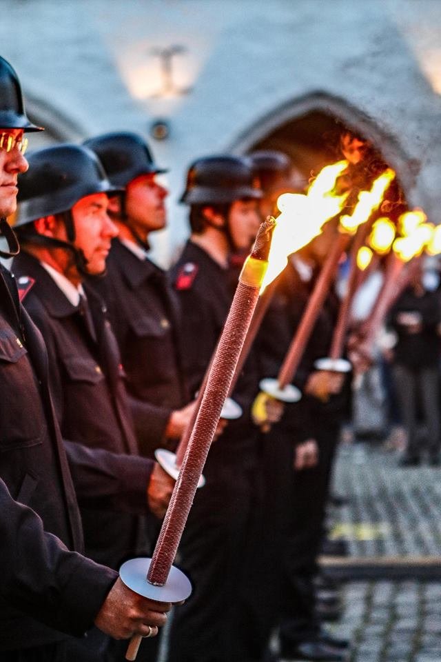Zapfenstreich zum Abschluss des Lambertusmarktes. Feuerwehrleute halten Fackelstäbe in den Händen.