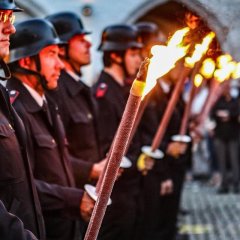 Zapfenstreich zum Abschluss des Lambertusmarktes. Feuerwehrleute halten Fackelstäbe in den Händen.