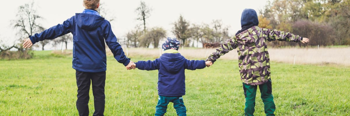 Kinder stehen Hand in Hand auf einer Wiese