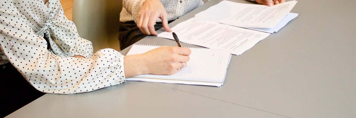 Zwei Personen sitzen mit Unterlagen an einem Tisch.