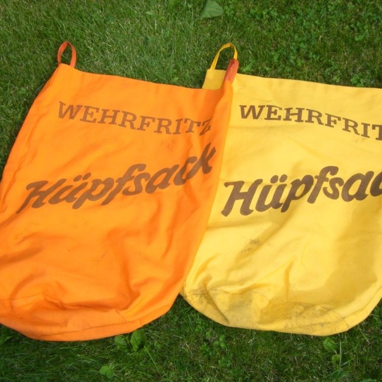 Hüpfsäcke (Stoff): Dieser strapazierfähige Kinder-Hüpfsack ist hergestellt aus robustem Markisenstoff, gelb- bzw. orangefarben, und verfügt über Haltegriffe.