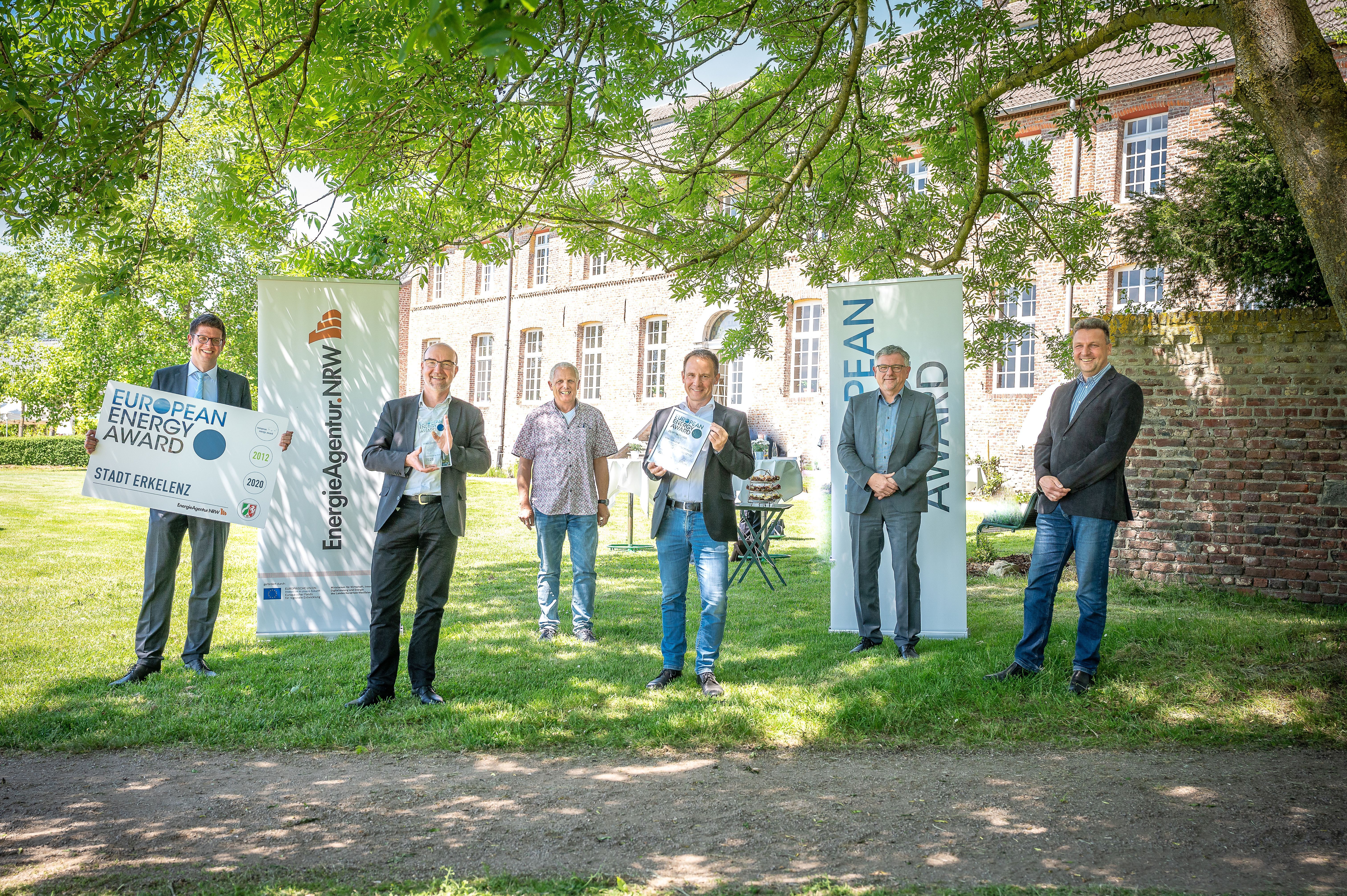 Bürgermeister Stephan Muckel zeigt zusammen mit Mitarbeitern der Verwaltung die Auszeichnung "European Energy Award" vor Haus Hohenbusch