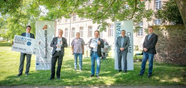 Bürgermeister Stephan Muckel zeigt zusammen mit Mitarbeitern der Verwaltung die Auszeichnung "European Energy Award" vor Haus Hohenbusch