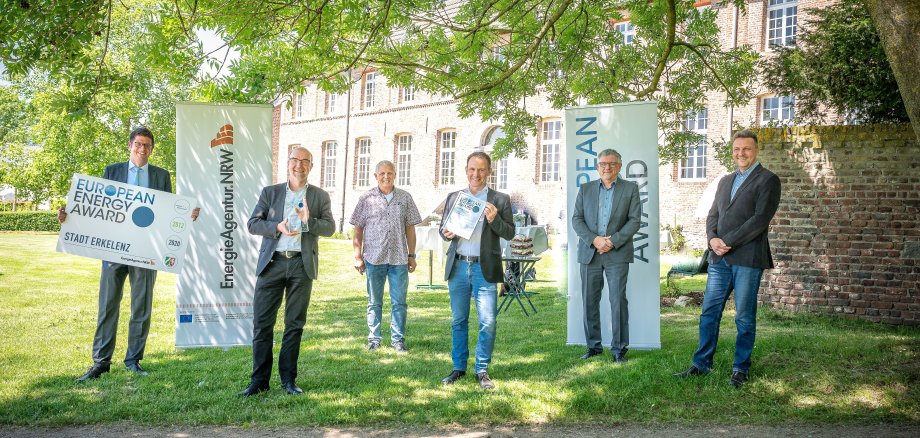 Bürgermeister Stephan Muckel zeigt zusammen mit Mitarbeitern der Verwaltung die Auszeichnung "European Energy Award" vor Haus Hohenbusch