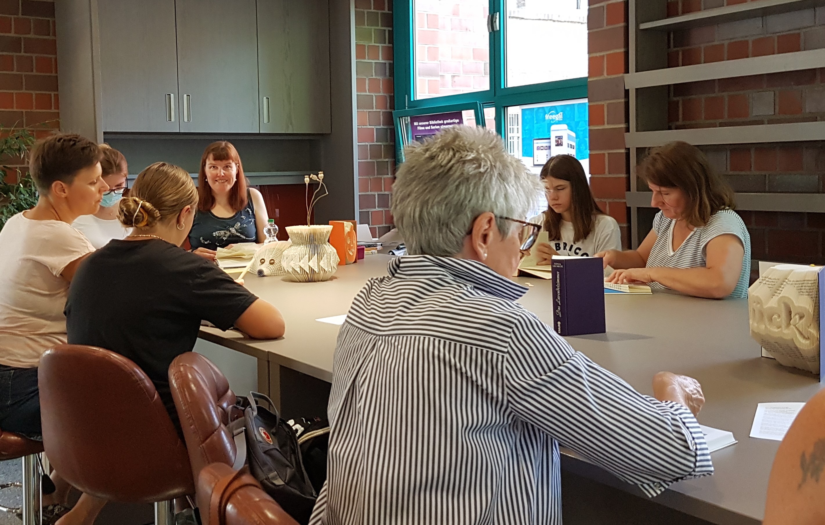 Menschen basteln Kreatives aus alten Büchern beim 1. Workshop im KreativRaum der Stadtbücherei Erkelenz.