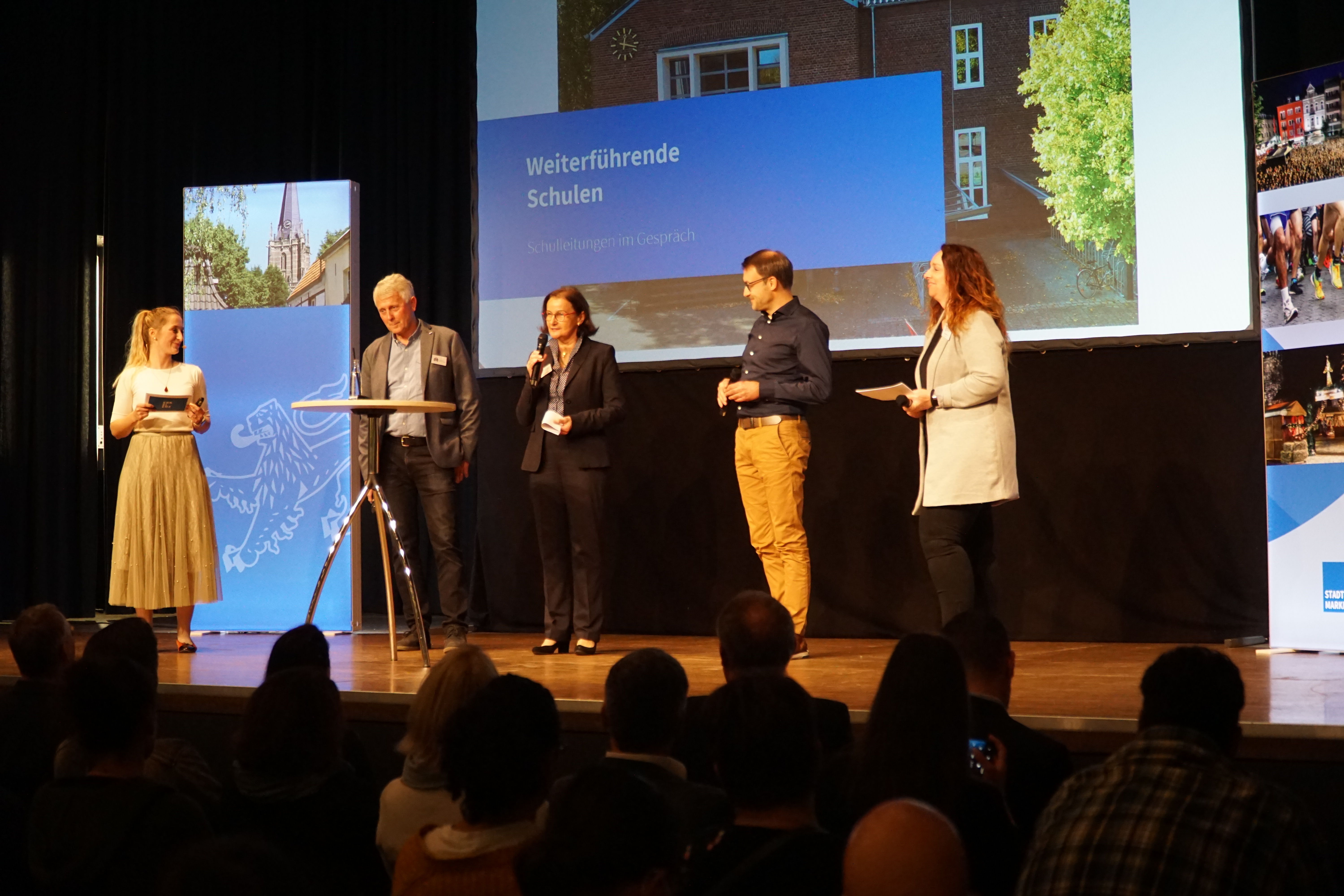 Während der Talkrunde der Schulleitungen auf der Bühne: (v.l.n.r.) Jessica Starzetz, Moderation, Erich Konietzka, Schulleitung Gemeinschaftshauptschule, Silvia Rudig, Schulleitung Europaschule, Jörg Diepenthal, Schulleitung Cusanus-Gymnasium und Anja Peters, Schulleitung Cornelius-Burgh-Gymnasium