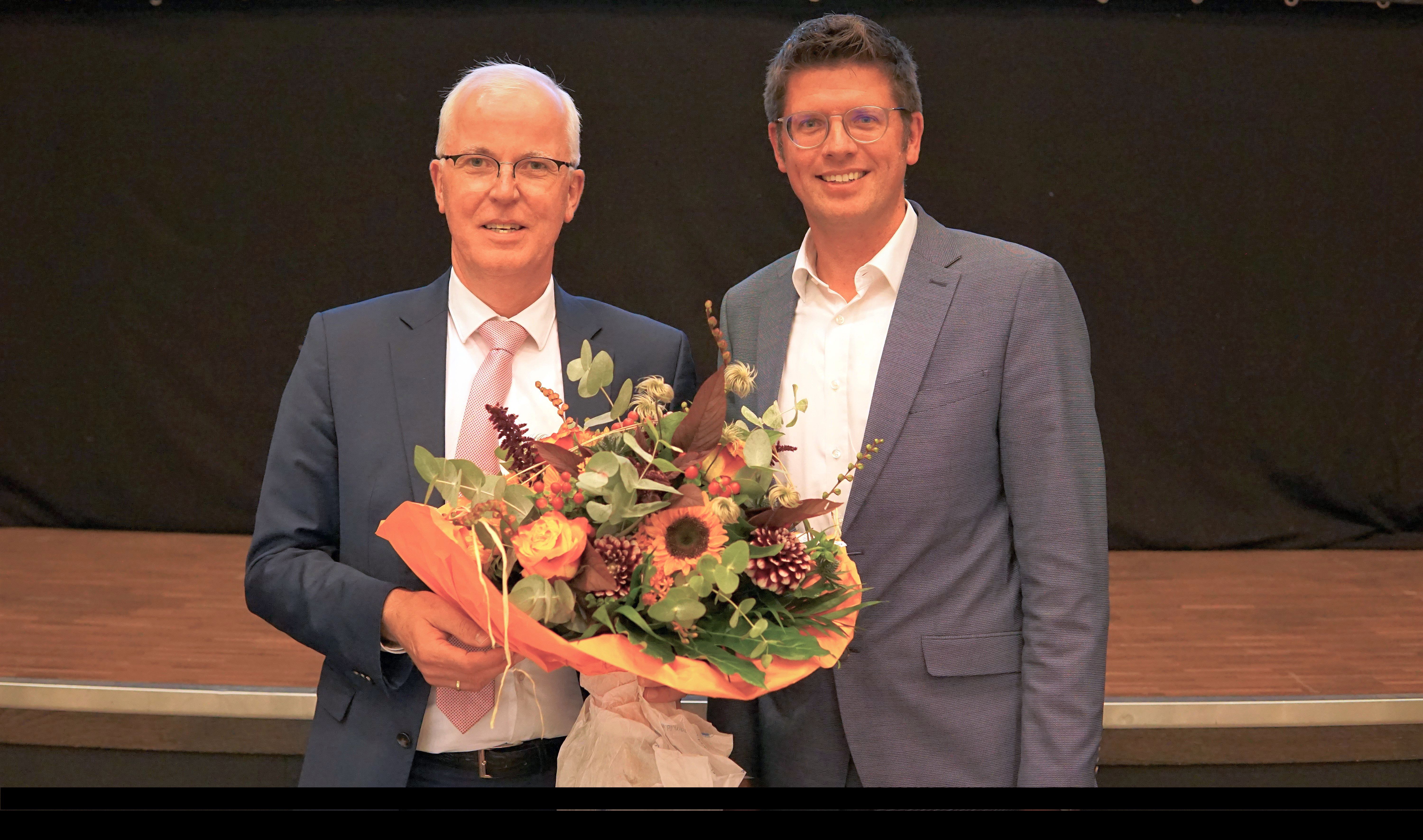 Bürgermeister Stephan Muckel gratuliert Herrn Dr. Hans-Heiner Gotzen mit einem Blumenstrauß zu dessen Wiederwahl zum Ersten Beigeordneten
