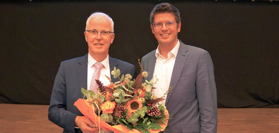 Bürgermeister Stephan Muckel gratuliert Herrn Dr. Hans-Heiner Gotzen mit einem Blumenstrauß zu dessen Wiederwahl zum Ersten Beigeordneten