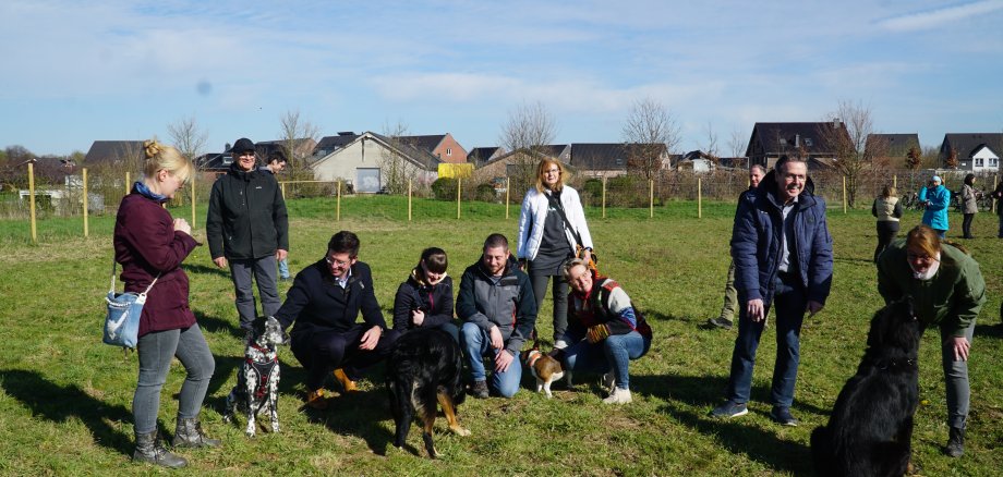 Bürgermeister Stephan Muckel mit Hunden und Hundebesitzern auf der Hundewiese.