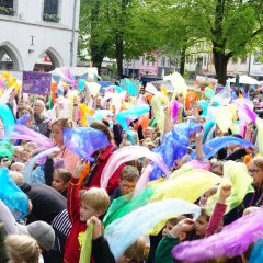 Schülerinnen und Schüler winken mit bunten Tüchern