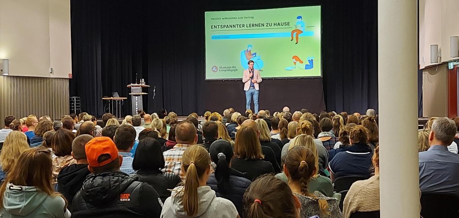 Stadthalle voller Menschen mit Blick auf Präsentation