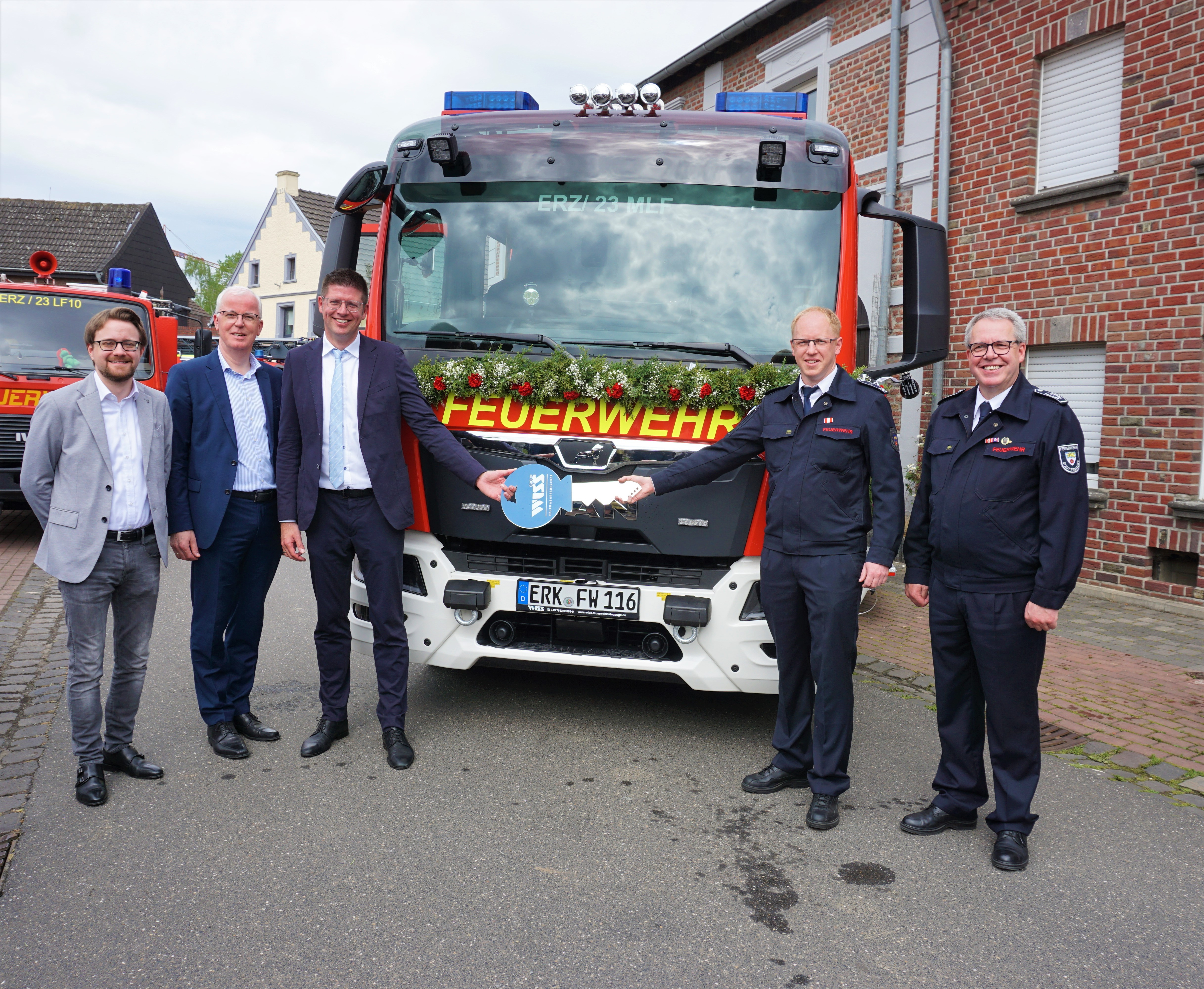 Gruppenbild vor Feuerwehrfahrzeug mit Schlüsselübergabe