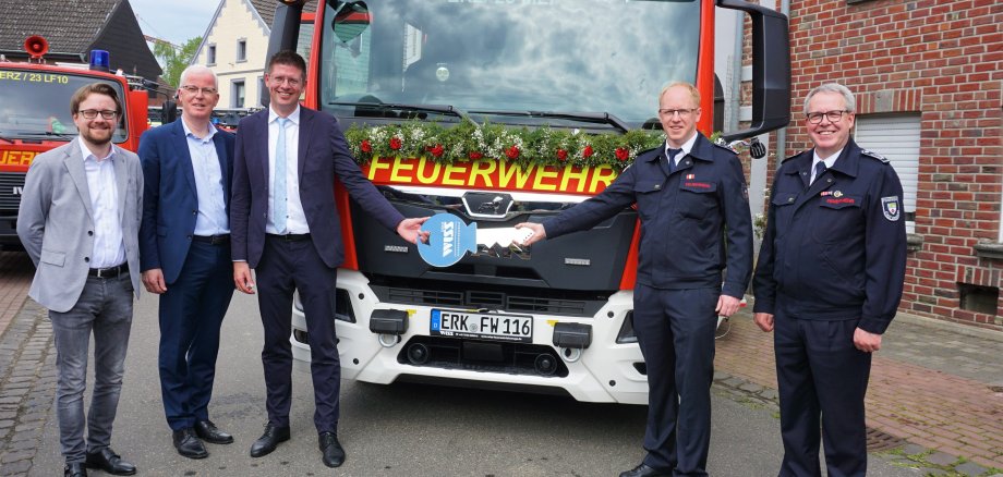 Gruppenbild vor Feuerwehrfahrzeug mit Schlüsselübergabe