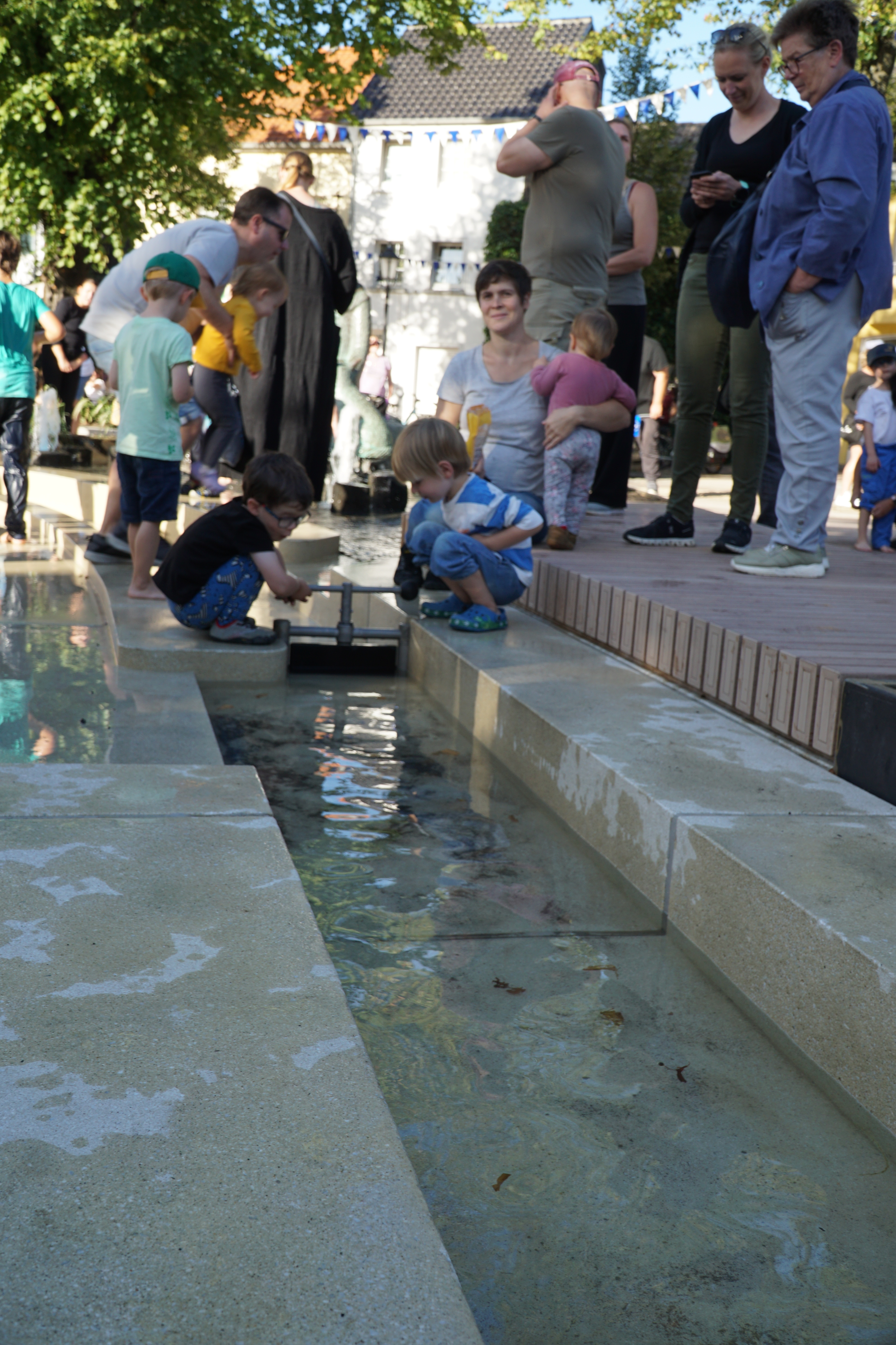 Kinder probieren die Wassersperre im Wasserspiel aus