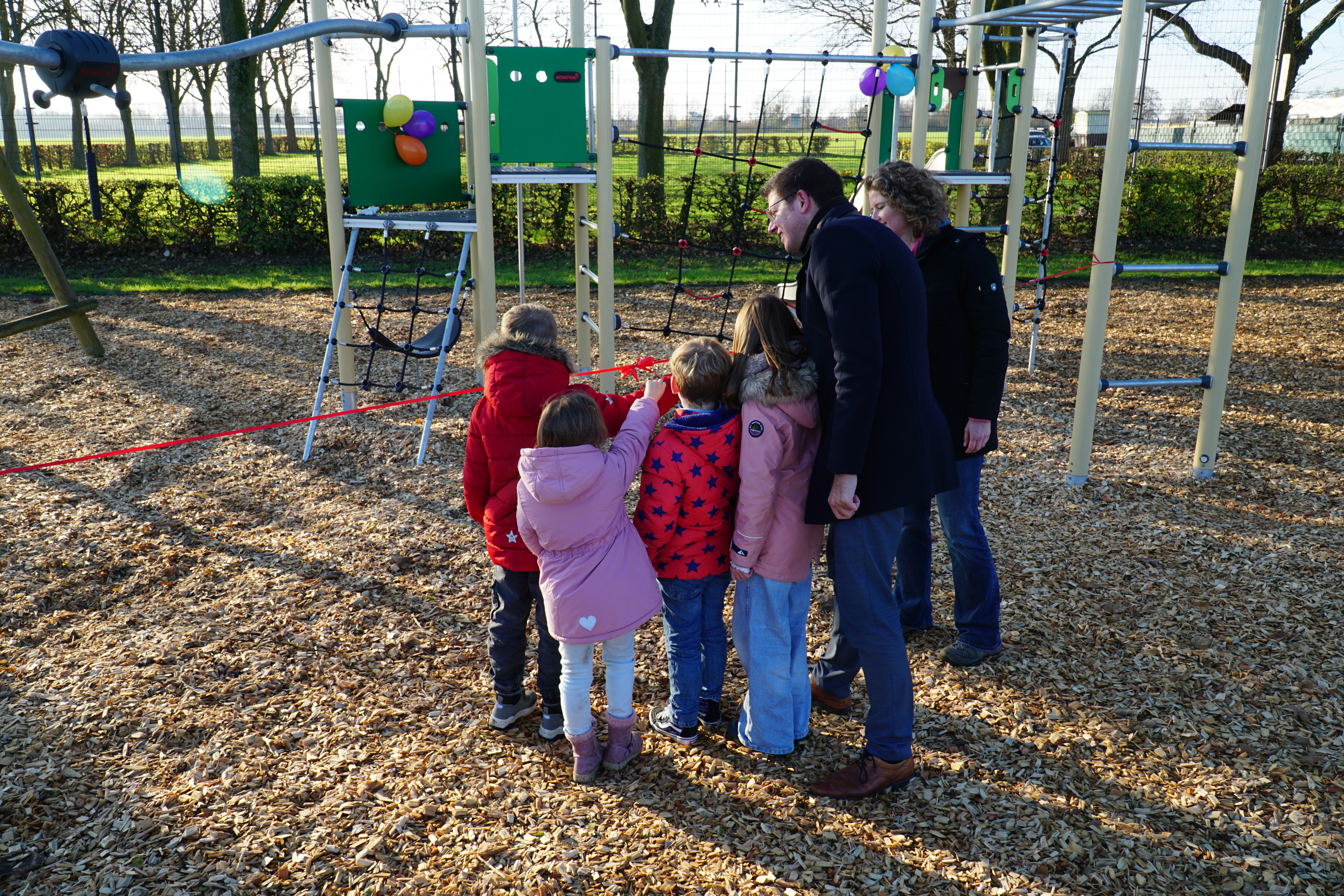 Kinder und Bürgermeister schneiden rotes Band durch