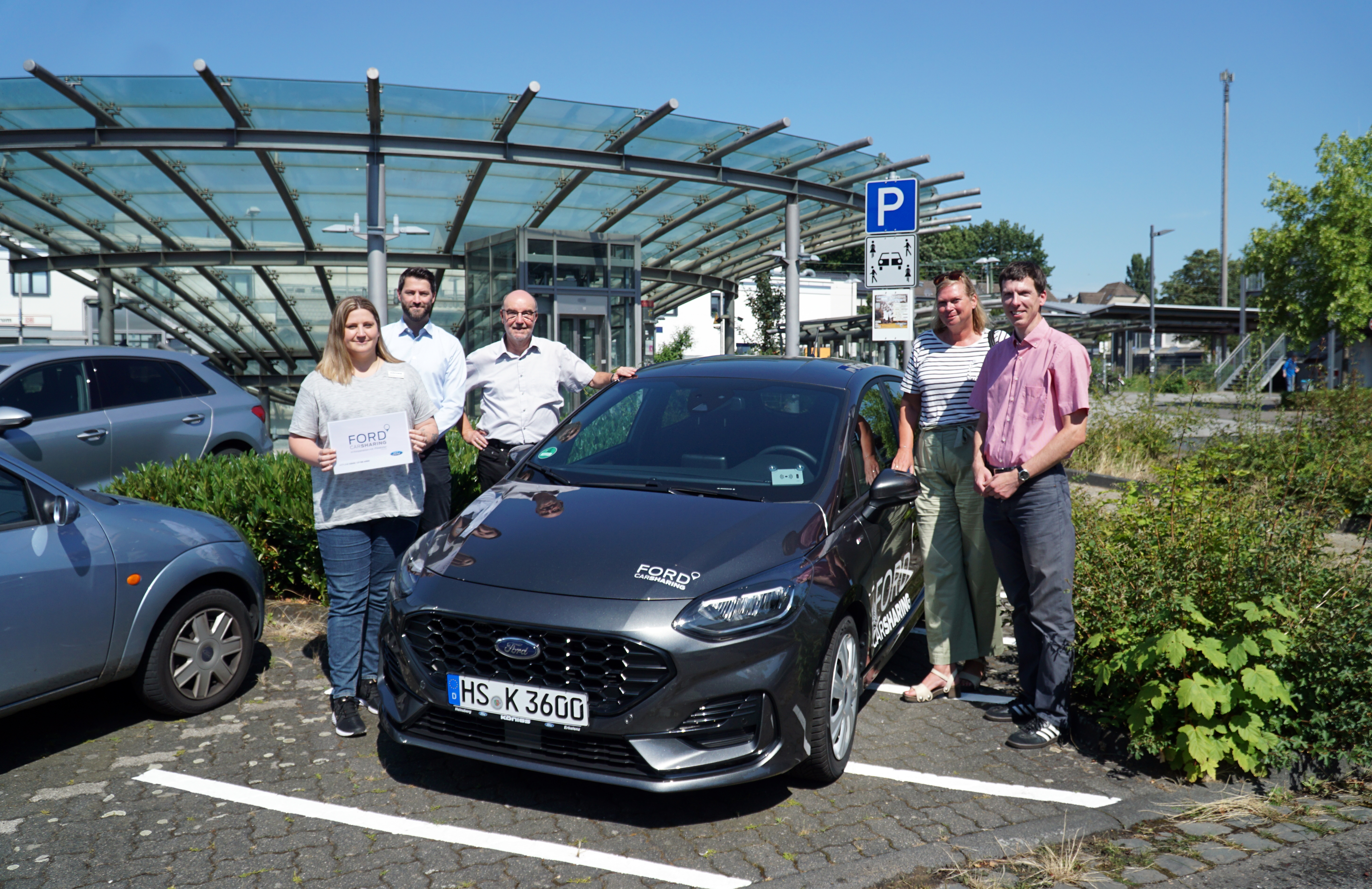 Menschen und ein Auto am Bahnhof