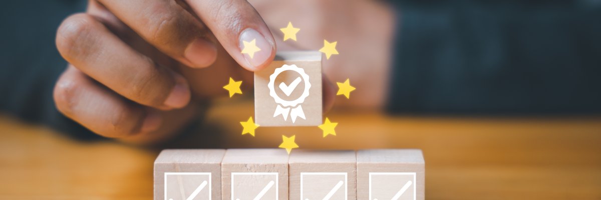 Mann hält Holzwürfel in der Hand, abgebildet ist ein Abzeichen