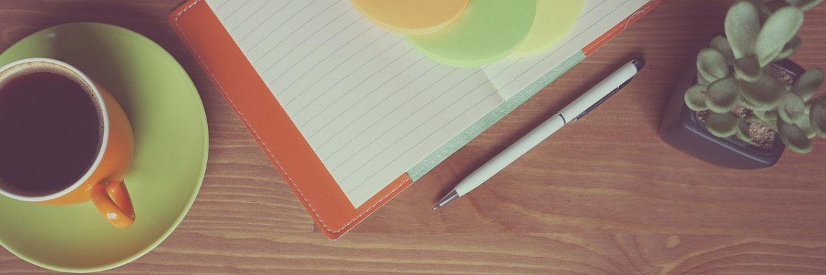 Tisch mit Kaffeetasse und Schreibblock