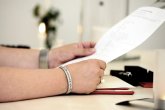 Person sitzt an einem Tisch und hält einen Zettel in der Hand