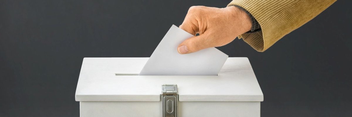 Wahlurne_Zerbor_94341686 - Mann wirft Stimmzettel in Wahlurne Jemand wirft Stimmzettel in eine Wahlurne