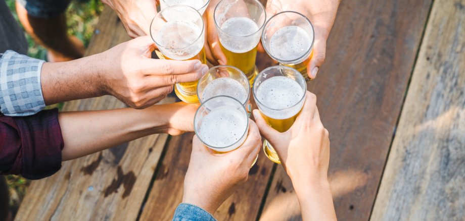 Cropped shot of people holding beer glasses celebrating in the summer camping party outdoor. Friends clinking bottle of beer during camping outdoor Cropped shot of people holding beer glasses celebrating in the summer camping party outdoor. Friends clinking bottle of beer during camping outdoor