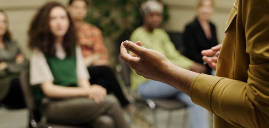 Hands of young business coach explaining information to group of employees