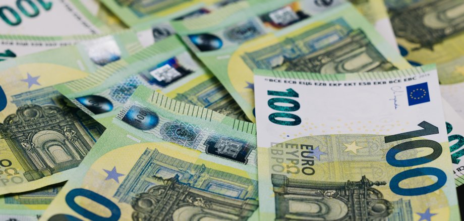 Close-up view of scattered 100 euro banknotes on a flat surface, showcasing intricate designs and security features of European currency