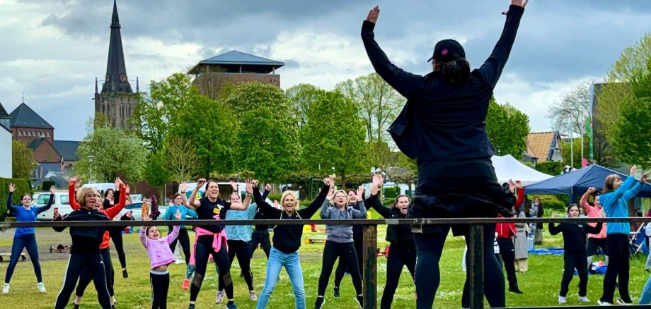Menschen machen Sport im ziegelweiherpark. Im Hintergrund Kirchturm und Burg