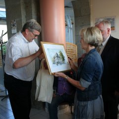 Bürgermeiser Peter Jansen überreicht der Schulleiterin der Partnerschule in Saint-James ein Gemälde vom Alten Rathaus Erkelenz