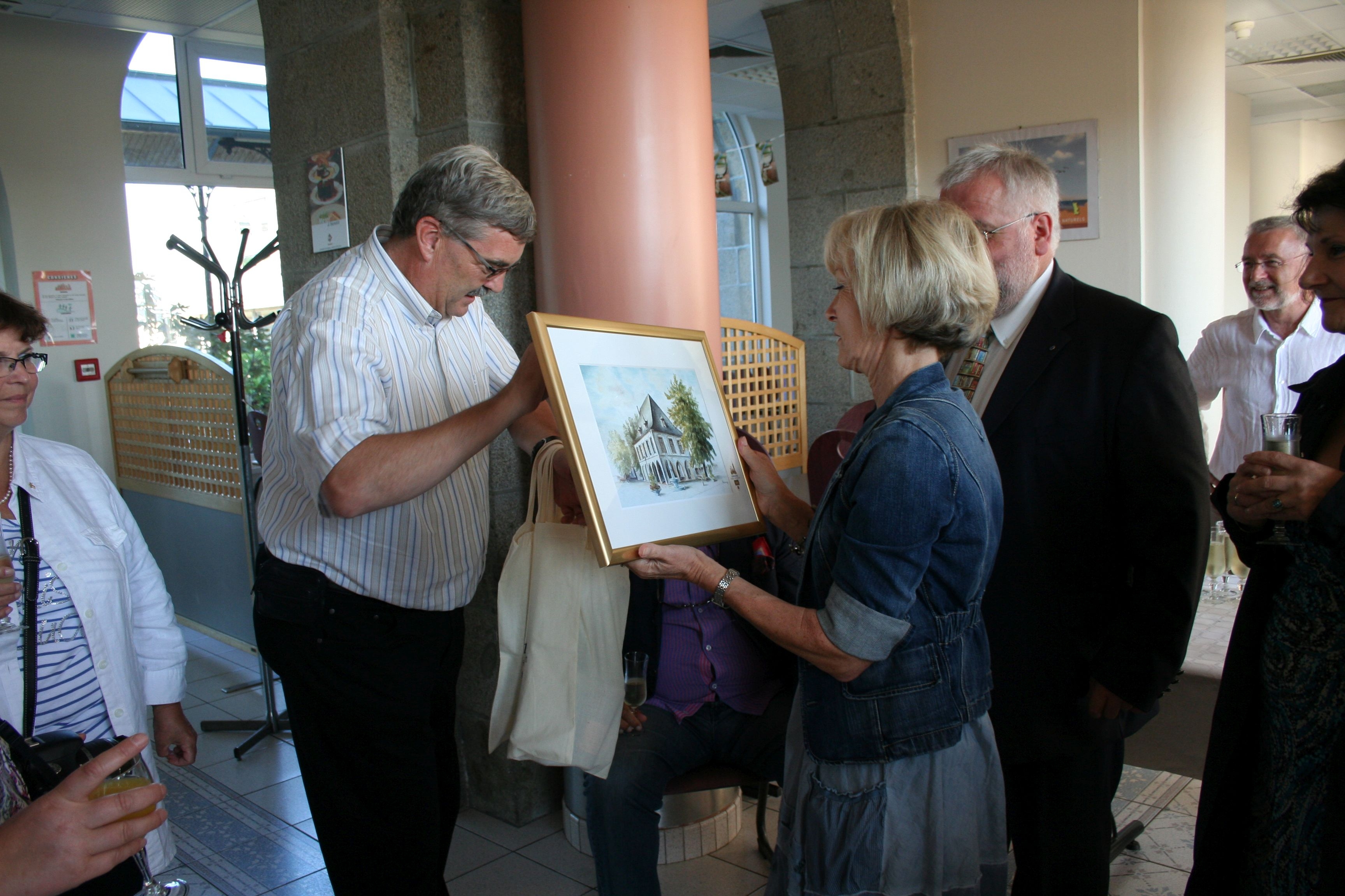 Bürgermeiser Peter Jansen überreicht der Schulleiterin der Partnerschule in Saint-James ein Gemälde vom Alten Rathaus Erkelenz