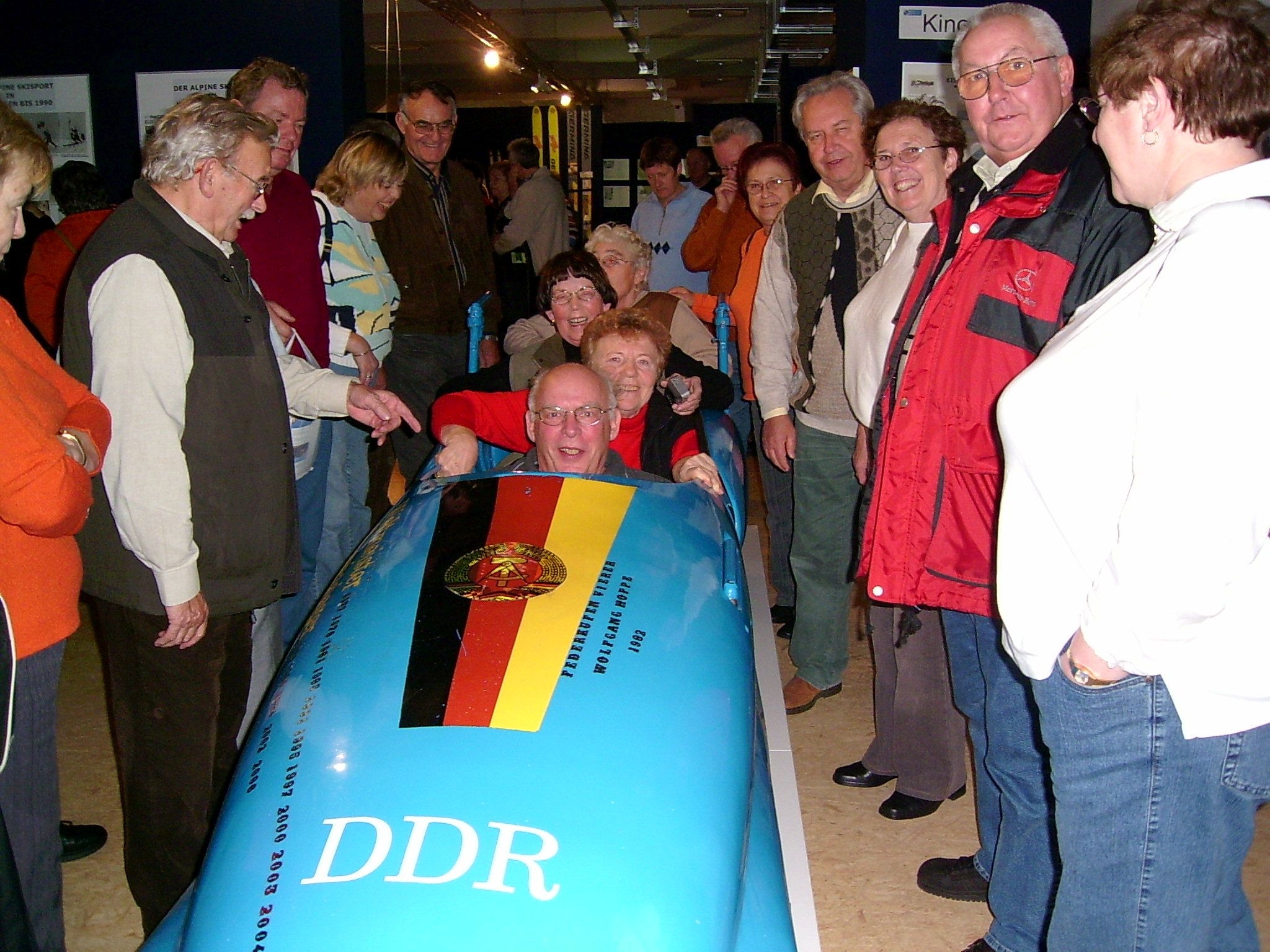 Besucher im Wintersportmuseum in Oberhof/Thüringen, vier von ihnen sitzen in einem ehemaligen DDR-Bob.